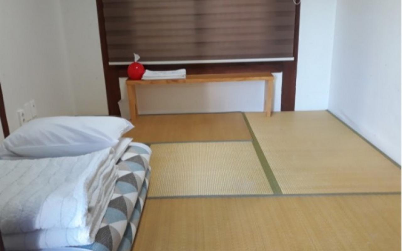 다다미 바닥에 이불 세트와 나무 선반이 놓인 봄 객실 침실