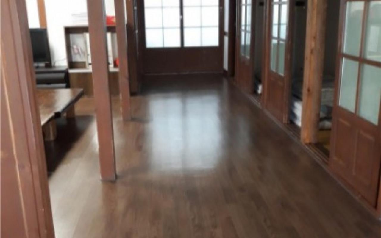 원목 기둥과 미닫이문이 늘어선 넓은 거실 마루 공간