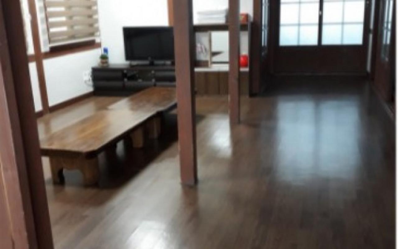 긴 좌식 원목 테이블과 TV가 보이는 사랑채 마루 거실