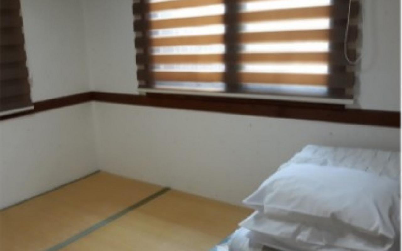 블라인드가 내려진 창문과 침구가 개어져 있는 온돌방 침실