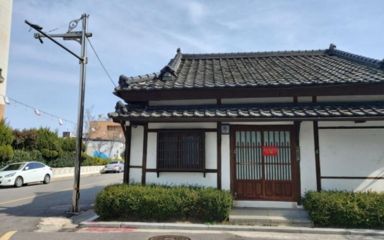 기와지붕과 목재 창살 문이 있는 한옥 건물의 도로변 외관 전경입니다.