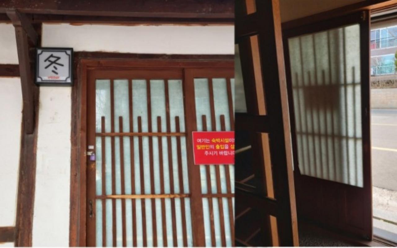 한자 겨울 동 자가 적힌 문패와 안내문이 붙은 전통 목재 미닫이문 입구입니다.
