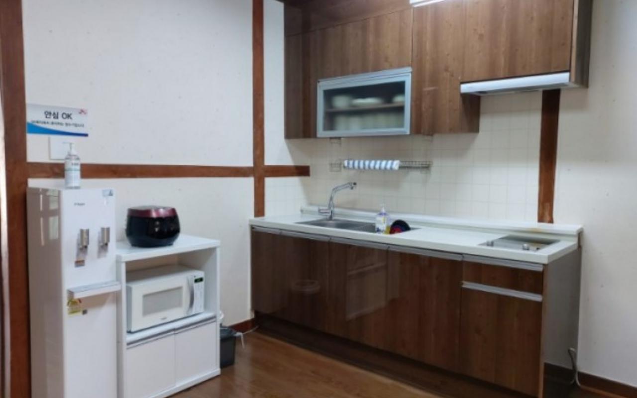 싱크대, 상부 수납장, 정수기, 전자레인지, 밥솥이 갖춰진 주방 공간입니다.